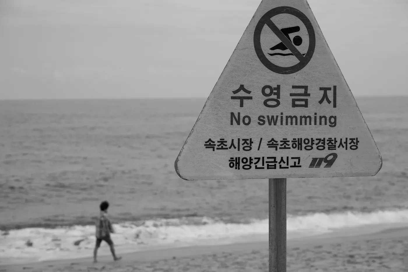 Warning sign with “No Swimming” written in several languages, placed near a hazardous or restricted water area.