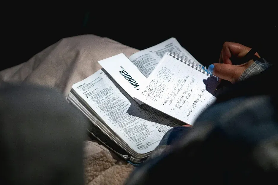 Close-up of a person writing notes in a notebook during a meeting or study session